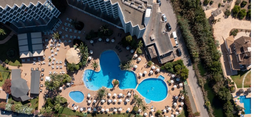 Vista aérea de un hotel con piscina en la costa